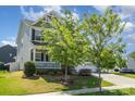 Inviting two-story home featuring a front porch, lush lawn, and mature trees at 4406 Huntley Glen Dr, Pineville, NC 28134
