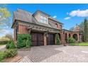 Three car garage with brick paver driveway, wooden doors, and mature landscaping at 4465 3Rd Nw St, Hickory, NC 28601
