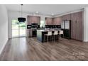 Modern kitchen features an island with seating and stainless steel appliances with dark gray cabinets at 6907 Lancaster Hwy, Waxhaw, NC 28173