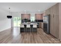 Open kitchen featuring a stylish island, stainless steel appliances, tile backsplash, and wood flooring at 6907 Lancaster Hwy, Waxhaw, NC 28173