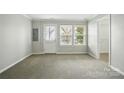 Bright living room with neutral carpet, natural light from a window, and a white door leading outside at 7753 Jackson Pond Dr, Charlotte, NC 28273