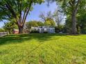 Quaint single-story home on a lush green lawn with mature trees at 1142 Mona Dr, Charlotte, NC 28206