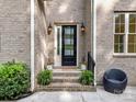 Charming front door with sidelights, complemented by potted plants and a cozy chair at 1409 Bloomsberry Ln, Waxhaw, NC 28173