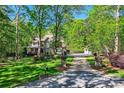 Charming home with stone and brick exterior, manicured lawn, trees and long driveway at 14131 Lea Point Ct, Huntersville, NC 28078