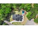 Aerial view of a luxurious home with a sparkling swimming pool surrounded by lush greenery and mature trees at 220 Palm Cove Way, York, SC 29745