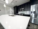 Modern kitchen island with white countertops, sink and stainless steel appliances at 222 S Caldwell St # 1801, Charlotte, NC 28202