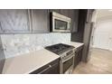 Close up view of the modern kitchen's stainless steel stove and white backsplash at 222 S Caldwell St # 1801, Charlotte, NC 28202