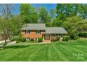 Classic brick home with a manicured lawn, mature trees, and black shutters on a sunny day at 2815 Burnt Mill Rd, Charlotte, NC 28210