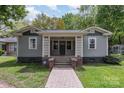 Charming home with a welcoming front porch, gray siding, and manicured lawn with a brick walkway and foundation at 303 S Iredell Ave, Spencer, NC 28159