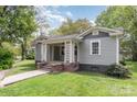 Charming home with a welcoming front porch, gray siding, and manicured lawn with a brick walkway and foundation at 303 S Iredell Ave, Spencer, NC 28159