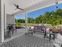 A covered outdoor patio features stylish black and white furniture, ceiling fan and a view of the backyard at 4012 Moxie Way, Charlotte, NC 28215