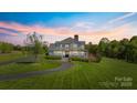Gorgeous home with a wrap-around porch, mature trees, and a long winding driveway at sunset at 1065 Hunter Bridge Rd, Stony Point, NC 28678