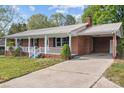 Charming single-story red brick home featuring a metal roof, a front porch, and a long concrete driveway at 1195 Ralph B Keener Rd, Lincolnton, NC 28092