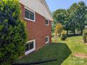 Well-maintained side yard with lush greenery, landscaping, and visible exterior brick wall at 351 Glenwood Dr, Mooresville, NC 28115
