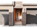Modern townhome entrance features a brick facade, wood accents, and a dark-colored garage door at 4109 Bryant Terraces Dr, Charlotte, NC 28208