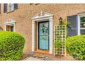 Stylish front door with white trim and wreath detail, complemented by lush green bushes and a lattice trellis at 4607 Hedgemore Dr # H, Charlotte, NC 28209