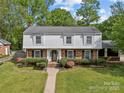 Classic two-story home features a landscaped front yard, brick and shingle facade, and inviting walkway to the front door at 6035 Idlebrook Dr, Charlotte, NC 28212