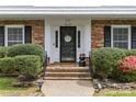 Inviting front entrance with brick steps, manicured hedges, and decorative door with sidelights, blending classic charm with curb appeal at 6035 Idlebrook Dr, Charlotte, NC 28212