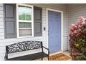 Close-up of the home's entrance featuring a gray door, window, and a welcoming bench at 8820 First Run Ct, Charlotte, NC 28215