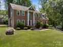Two-story brick home featuring a red door, landscaped front yard and lush green trees at 9000 Stourbridge Dr, Huntersville, NC 28078