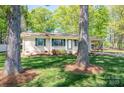 Lovely brick home with green shutters, a front porch, and a carport, nestled among mature trees at 1 Horace Grigg Cir, Shelby, NC 28152
