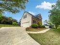 View of home with a two car garage, green lawn, and bordered by mature landscaping at 1121 Setter Se Ln, Concord, NC 28025