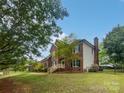 Side view of home, showcasing brick, siding, mature trees, and a manicured lawn at 1121 Setter Se Ln, Concord, NC 28025