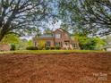 Lovely red brick home from ground level, showcasing mature trees and front yard at 1121 Setter Se Ln, Concord, NC 28025