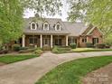 Elegant brick home featuring a welcoming front porch, well-maintained lawn, and inviting curb appeal at 1126 Concord Rd, Davidson, NC 28036