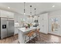 Modern kitchen featuring white cabinets, stainless steel appliances, a center island with bar seating, and wood flooring at 1198 Links Crossing Dr # 162P, Monroe, NC 28112