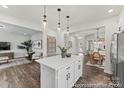 Open-concept kitchen with a large island, white cabinets, dark wood flooring, and a view into the living area at 1198 Links Crossing Dr # 162P, Monroe, NC 28112