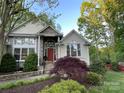 Stylish home entrance featuring stone accents, bright red door, and mature landscaping at 121 General Pemberton St, Stanley, NC 28164