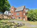 Backyard brick house featuring a driveway, partial fence, and a charming architectural structure at 121 W 11Th St, Oakboro, NC 28129