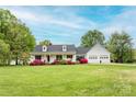 Beautiful white home featuring a welcoming front porch, lush landscaping, and an attached two-car garage at 123 Coachman Loop, Statesville, NC 28625