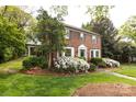 Brick two-story home with white trim, shuttered windows, and professionally landscaped yard at 1943 S Wendover Rd, Charlotte, NC 28211