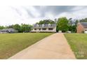 Spacious front yard leading to a quaint yellow house with a long driveway and lush green surroundings at 1990 Country Club Dr, Lancaster, SC 29720