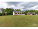 Charming yellow home with a welcoming front porch and a well-manicured lawn, set against a backdrop of trees at 1990 Country Club Dr, Lancaster, SC 29720