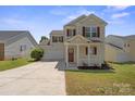 Inviting two-story home with a covered porch, red shutters, attached garage, and well-maintained lawn at 6135 Raisin Tree Ln, Charlotte, NC 28215