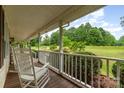 Relaxing covered porch with white rocking chairs and a view of the green, tree-lined yard at 6769 Highway 557 None, Clover, SC 29710