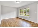 Sunlit living room boasts hardwood floors and a large window overlooking a green residential street at 801 Bilmark Ave, Charlotte, NC 28213