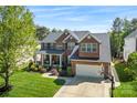 A two-story brick house with a well-kept lawn, a basketball hoop, and a two-car garage on a sunny day at 9715 Aragorn Nw Ln, Charlotte, NC 28269