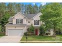 Charming two-story home with a well-maintained lawn, mature trees, and a red front door at 14220 Stewarts Bend Ln, Charlotte, NC 28277