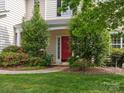 Inviting front porch with a red door, lush landscaping, and a well-maintained walkway at 14220 Stewarts Bend Ln, Charlotte, NC 28277