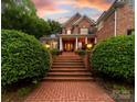 Charming brick two-story home with front porch and steps leading to the entry under a colorful sunset sky at 17040 Jetton Rd, Cornelius, NC 28031