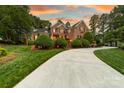 Charming brick two-story home with manicured lawn and lush landscaping under a colorful sunset sky at 17040 Jetton Rd, Cornelius, NC 28031