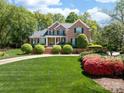 Charming brick two-story home with manicured lawn and lush landscaping under a sunny, partly cloudy sky at 17040 Jetton Rd, Cornelius, NC 28031