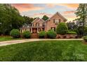 Charming brick two-story home with manicured lawn and lush landscaping under a colorful sunset sky at 17040 Jetton Rd, Cornelius, NC 28031