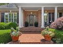 Charming front porch with brick steps, white columns, and colorful potted flowers create an inviting entry at 17040 Jetton Rd, Cornelius, NC 28031