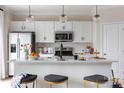 Bright kitchen with white cabinetry, a stainless steel refrigerator, and a central island with seating at 2021 Endeavor Run, Charlotte, NC 28269