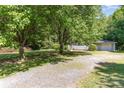 Lovely ranch style home showing a gravel driveway leading to an attached garage surrounded by mature shade trees at 3332 Celanese Rd, Rock Hill, SC 29732
